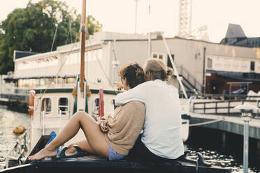 Boyfriend pointing while embracing girlfriend on houseboat at harbor - MASF21315