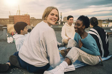 Porträt von Freundinnen, die sich bei Sonnenuntergang auf der Terrasse eines Gebäudes vergnügen - MASF21334