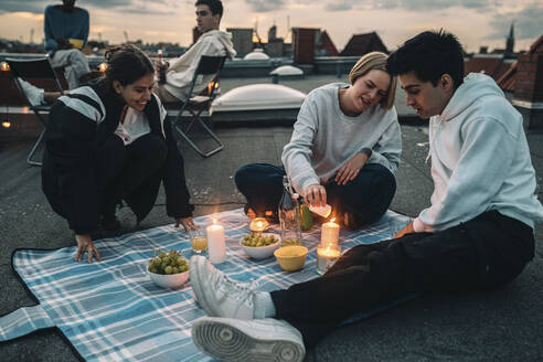 Männliche und weibliche Freunde genießen auf dem Dach eines Gebäudes bei Sonnenuntergang - MASF21356