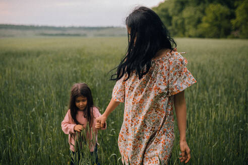 Glückliche Mutter mit Kind auf einem Feld in der Abenddämmerung - CAVF91985