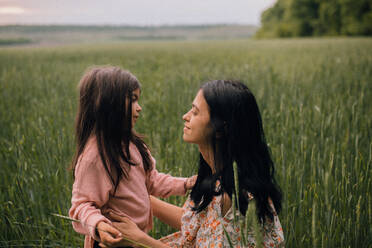 Smiling mother and daughter and talking in field - CAVF91989