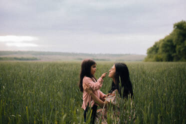 Smiling mother and daughter and talking in field - CAVF91991