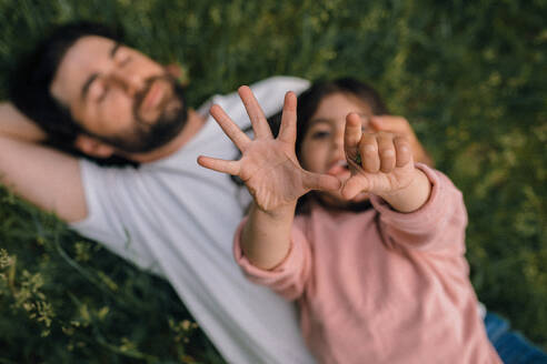 Daughter counting on fingers with dad in field - CAVF91992