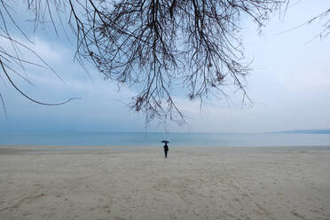 Frau, die mit einem Regenschirm zum Meer geht - CAVF92001