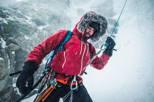 A male ice climber pulls a rope after climbing and rappelling a route - CAVF92075