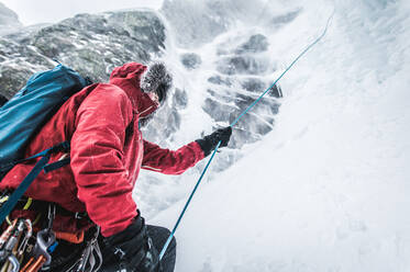 Ein männlicher Eiskletterer zieht ein Seil, nachdem er eine Route geklettert und abgeseilt ist - CAVF92076