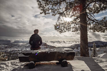 Frau sitzt auf schneebedeckter Bank mit Blick auf den Bryce Canyon nach Schnee - CAVF92107