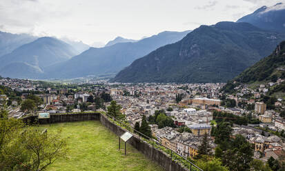 Stadtbild gegen Berg gesehen durch Parco Archeologico Botanico del Paradiso, Valchiavenna, Chiavenna, Provinz Sondrio, Lombardei, Italien - MAMF01541