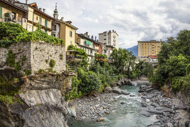 Der Fluss Mera fließt durch die Felsen neben den Gebäuden der Stadt gegen den Himmel, Valchiavenna, Chiavenna, Provinz Sondrio, Lombardei, Italien - MAMF01556