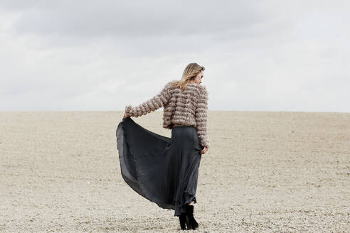 Mid erwachsene Frau trägt Rock und Fersen stehen am Strand gegen den Himmel - ERRF04900