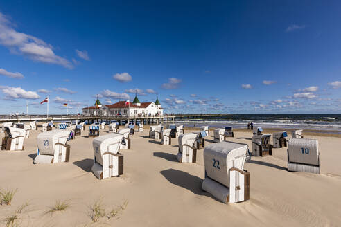 Deutschland, Mecklenburg-Vorpommern, Heringsdorf, Strandkörbe mit Kapuze am leeren Strand mit der Seebrücke Ahlbeck im Hintergrund - WDF06491