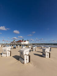 Germany, Mecklenburg-Western Pomerania, Heringsdorf, Hooded beach chairs on empty beach with Ahlbeck Pier in background - WDF06492