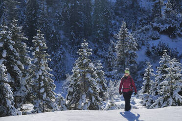 Frau spaziert in verschneiter Landschaft an einem sonnigen Tag - MRF02458