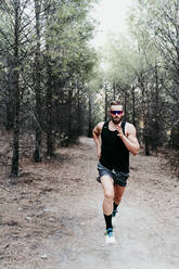 Gut aussehender männlicher Sportler, der auf einem Bergpfad im Wald läuft - EBBF02270