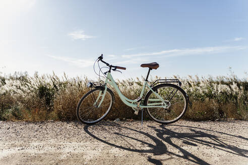Fahrrad geparkt in der Nähe von Reisfeld gegen den Himmel am Ebro-Delta an einem sonnigen Tag, Spanien - AFVF08065