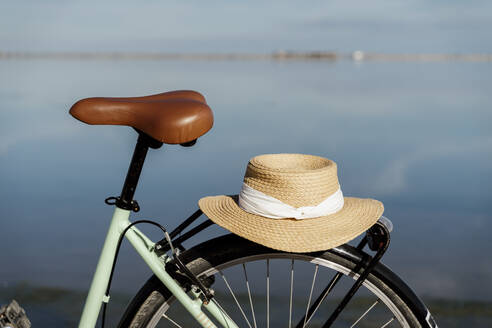 Beigefarbener Sonnenhut auf einem geparkten Fahrrad an einem sonnigen Tag im Ebro-Delta, Spanien - AFVF08069