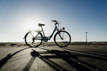 Silhouette eines am Strand von Fangar geparkten Fahrrads gegen den klaren Himmel im Sonnenlicht, Ebrodelta, Spanien - AFVF08073