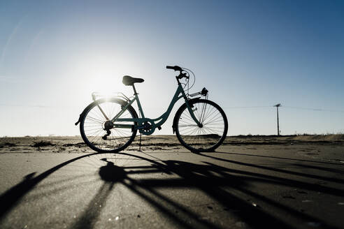 Silhouette eines am Strand von Fangar geparkten Fahrrads gegen den klaren Himmel im Sonnenlicht, Ebrodelta, Spanien - AFVF08073