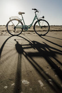 Fahrrad mit langem Schatten am Strand von Fangar bei klarem Himmel, Ebrodelta, Spanien - AFVF08074