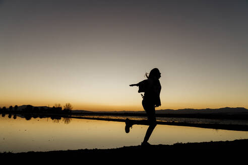 Junge Frau, die sich bei Sonnenuntergang im Ebro-Delta, Spanien, auf einem Bein dreht - AFVF08081