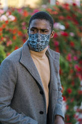 Man wearing face mask looking away while standing at park - EGAF01496