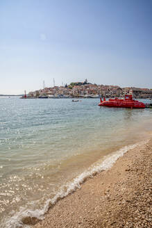 Rotes U-Boot am Strand vor dem Stadtbild von Primosten in Sibenik-Knin, Kroatien - MAMF01567