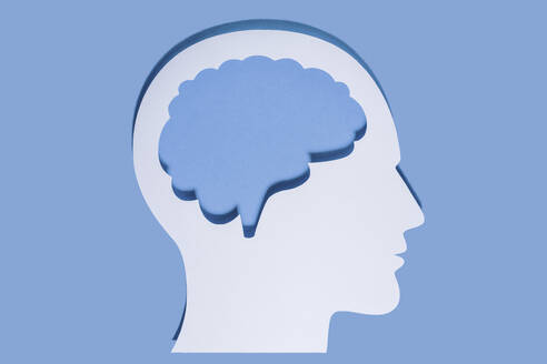 Nahaufnahme eines weißen menschlichen Kopfes und Gehirns aus Papier auf blauem Hintergrund - GEMF04576
