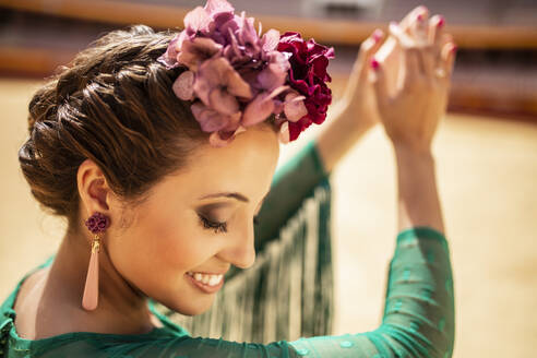 Nahaufnahme einer Flamenco-Tänzerin, die Blumen trägt und in die Hände klatscht - MIMFF00493