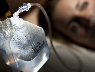 Nahaufnahme einer Patientin mit Infusion, die auf einem Bett in einer Krankenhausabteilung liegt - UKOF00112