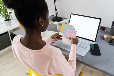 Modedesigner, der zu Hause im Büro sitzt und bunte Stoffmuster auswählt - GIOF10804