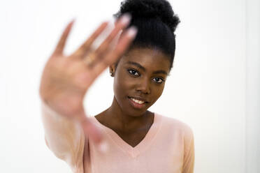 Frau zeigt Stopp-Geste im Stehen vor weißem Hintergrund - GIOF10829
