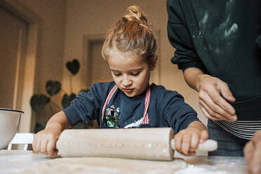 Mädchen hilft ihrer Mutter in der Küche beim Ausrollen von Teig für Zimtschnecken - DWF00557