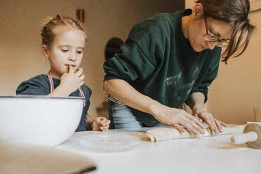 Mother rolling cinnamon roll dough with daughter at home - DWF00560