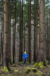 Männlicher Jogger in blauer Jacke läuft im Wald - STSF02764