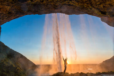 Mann hinter dem Seljalandsfoss-Wasserfall, Südisland, Island - MINF15784