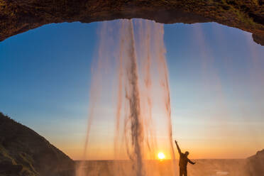 Mann hinter dem Seljalandsfoss-Wasserfall, Südisland, Island - MINF15785