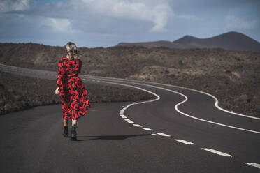 Frau in rotem Kleid geht auf der Straße in Los Hervideros, Lanzarote, Spanien - SNF00959