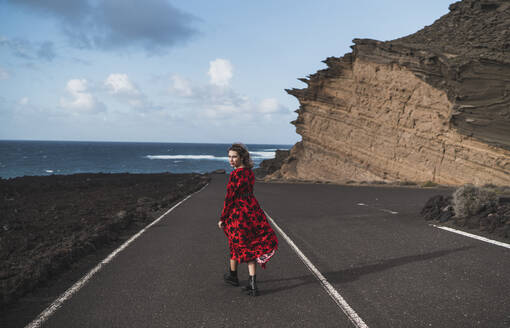 Junge Frau starrt beim Gehen auf der Straße in El Golfo, Lanzarote, Spanien - SNF00977