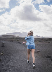 Junger Tourist lächelt beim Spaziergang auf dem Fußweg am Vulkan El Cuervo, Lanzarote, Spanien - SNF00991