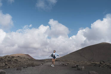 Frau mit ausgestreckten Armen, die sich auf dem Fußweg am Vulkan El Cuervo dreht, Lanzarote, Spanien - SNF01002