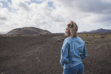 Lächelnder Tourist, der die Aussicht betrachtet, während er am Vulkan El Cuervo steht, Lanzarote, Spanien - SNF01003