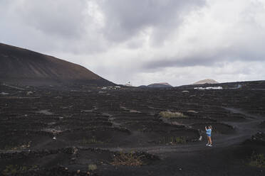 Female tourist exploring vineyard at Volcano El Cuervo, Lanzarote, Spain - SNF01004