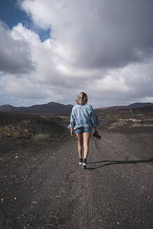 Tourist mit Kamera in der Hand auf dem Fußweg am Vulkan El Cuervo, Lanzarote, Spanien - SNF01005