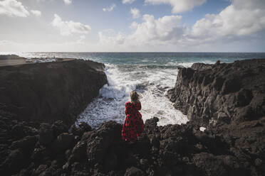 Woman looking at sea view while standing on mountain at Los Hervideros, Lanzarote, Spain - SNF01010