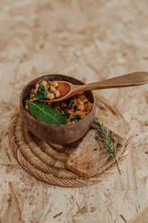 From above of vegetarian chickpea in bowl and slices of bread placed on table with basil for delicious lunch - ADSF20269