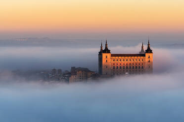 Drone Blick auf die Spitzen der alten Burgen zwischen dichten Wolken auf bunten Sonnenuntergang mit Hügeln am Horizont in Toledo - ADSF20274