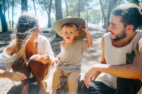 Multiethnische Paar Hippie und niedlichen kleinen Kind sitzen barfuß im Wald an einem sonnigen Tag und entspannen - ADSF20290