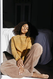 Woman with eyes closed resting while sitting by bed at home - TCEF01479