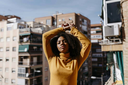 Woman stretching hand while standing at balcony - TCEF01489