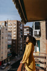 Young woman standing with eyes closed at balcony - TCEF01490